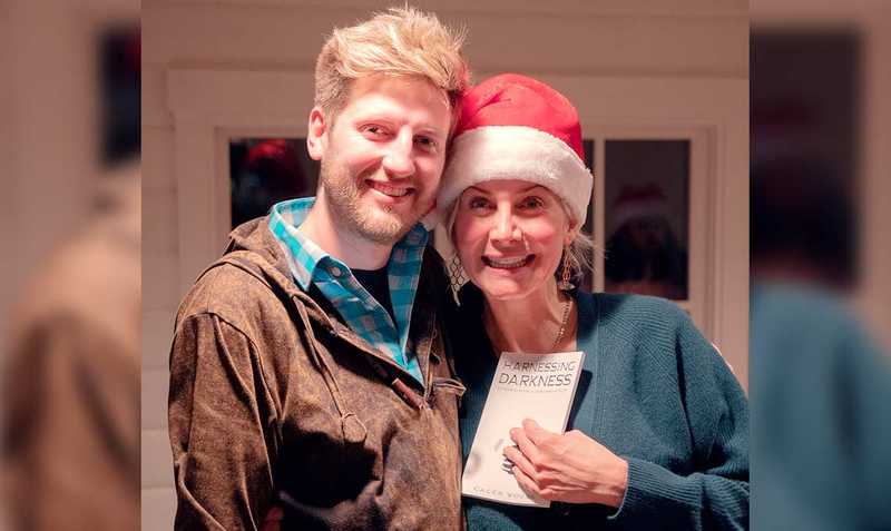 Caleb Woods and Elizabeth Mitchell holding the book Harnessing Darkness